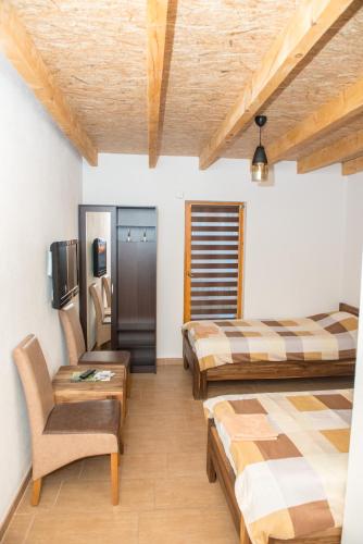 a room with two beds and a chair and a tv at Motel Orhideja in Donji Vakuf