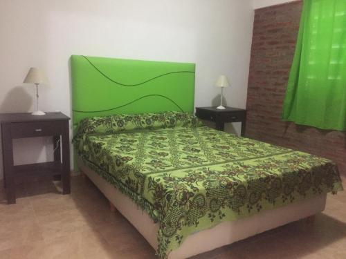 a bed with a green headboard in a bedroom at Complejo M&M in Bialet Massé