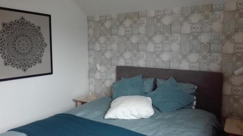 Una cama con almohadas azules y blancas en un dormitorio en B&B De Laak en Bilzen