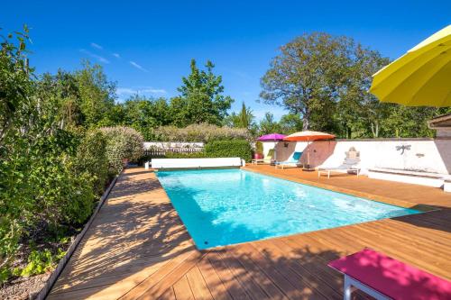 - une piscine sur une terrasse en bois avec un parasol dans l'établissement Le Mariecalou, à Meloisey