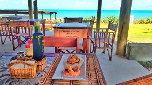 a plate of food on a table with the ocean in the background at Pousada Spa dos Amores in São Miguel do Gostoso