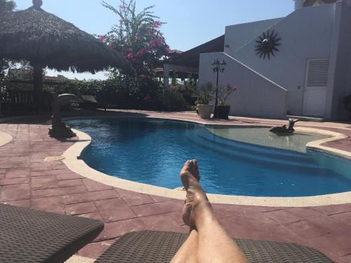 a person laying on a bed next to a swimming pool at Loft on the Pacific in La Union de Isidoro Montes de Oca