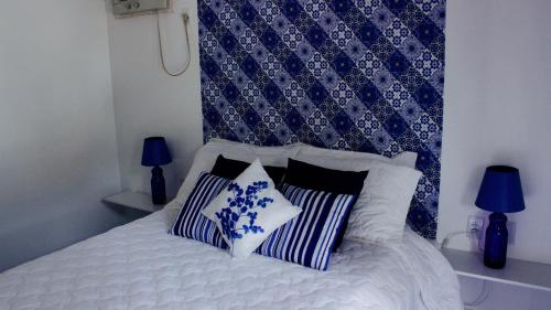 a bedroom with a bed with blue and white pillows at Pousada Narinari in Bombinhas