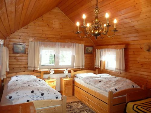 two beds in a log cabin bedroom with a chandelier at Apartamenty Widokowa in Korbielów