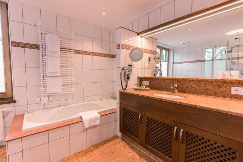 y baño con bañera y lavamanos. en Hotel & Gaststätte zum Erdinger Weißbräu en Múnich