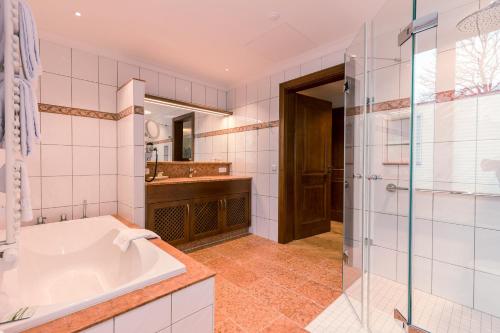 a bathroom with a tub and a glass shower at Hotel & Gaststätte zum Erdinger Weißbräu in Munich