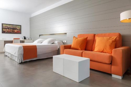 a bedroom with a bed and a orange couch at Hotel Spa Calagrande Cabo de Gata in Las Negras