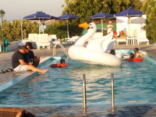 a group of people in a swimming pool with swans at Haritos Hotel - Geothermal Hot Swimming Pool in Mandrakion