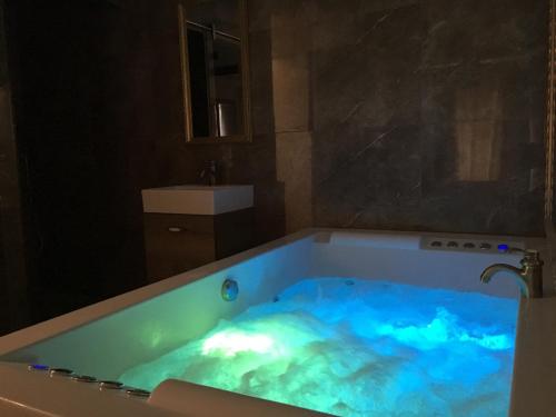 a bathroom with a tub filled with blue water at Central Business Apartments Jacuzzi in Belgrade