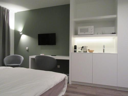 a bedroom with a bed and a desk and a tv at Hotel Muske Pitter in Mechelen