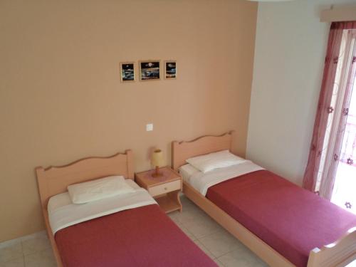 a bedroom with two beds and a table with a lamp at Kokkinos Apartments in Arillas