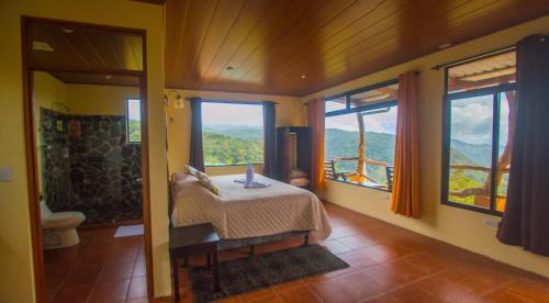 a bedroom with a bed in a room with windows at Rainbow Valley Lodge Costa Rica in Monteverde Costa Rica