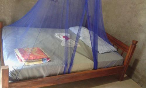 a small bed with a blue canopy and a blanket at Rosa's Lake Cabins in Mérida