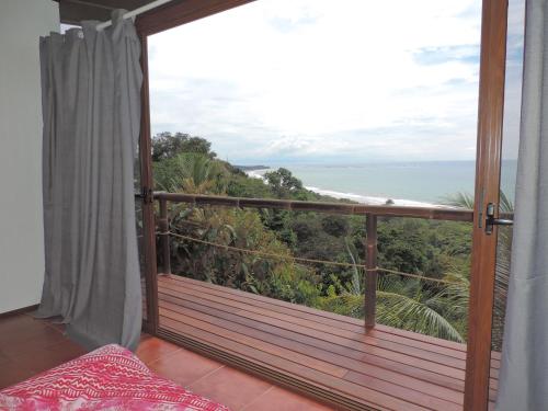 a room with a balcony with a view of the ocean at Ranchos Remo Lodge in Uvita