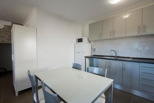 a kitchen with a table and chairs and a refrigerator at Cavaleiro Rota Costa Alentejana in Cavaleiro