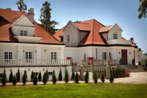ein großes weißes Haus mit rotem Dach in der Unterkunft Dwór Many, blisko do Suntago & DeepSpot in Many