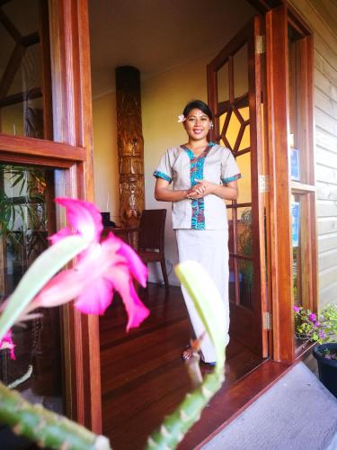 a woman standing on the porch of a house at Rapopo Plantation Resort in Kokopo
