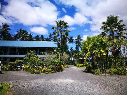 a parking lot in front of a building with palm trees at Rapopo Plantation Resort in Kokopo