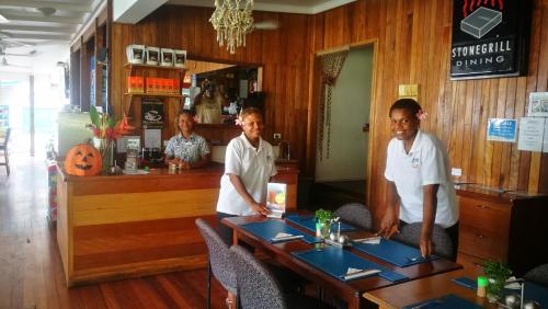 three men sitting at a table in a restaurant at Rapopo Plantation Resort in Kokopo