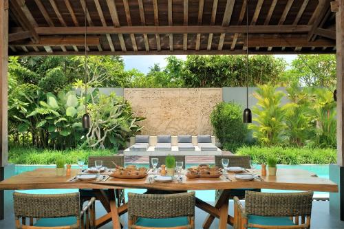 
a patio area with chairs, tables, and umbrellas at The Purist Villas & Spa Ubud in Ubud
