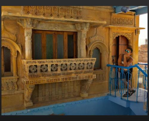 a man standing on a balcony of a toy building at The Blue House in Jodhpur