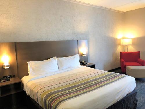 a hotel room with a bed and a red chair at Country Inn & Suites by Radisson, Mt Pleasant-Racine West, WI in Sturtevant