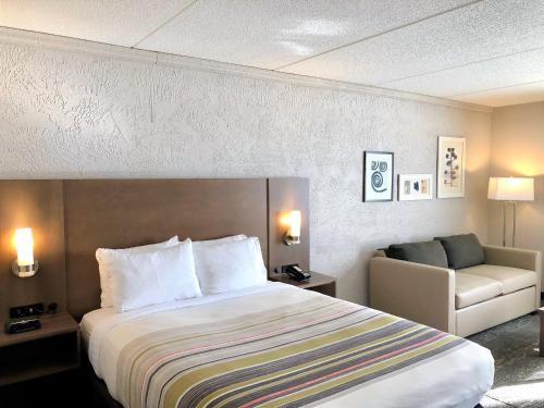 a hotel room with a bed and a couch at Country Inn & Suites by Radisson, Mt Pleasant-Racine West, WI in Sturtevant
