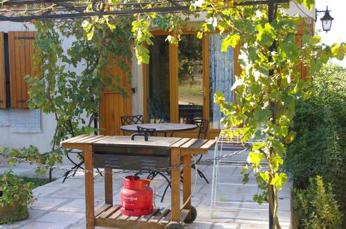 a patio with a wooden table and a red bucket at Gite La Paillote in Montauroux