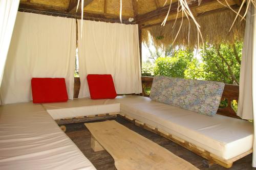 a porch with a couch and two red chairs at Gite La Paillote in Montauroux