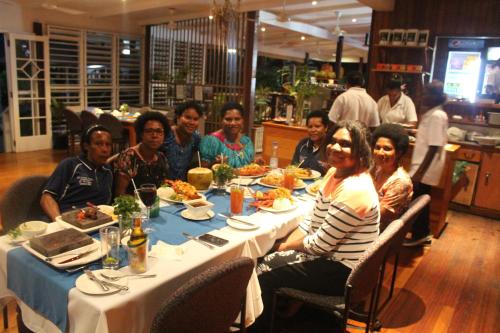 a group of people sitting at a table eating food at Rapopo Plantation Resort in Kokopo