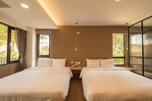 two beds in a room with two windows at Okra Villa in Kenting