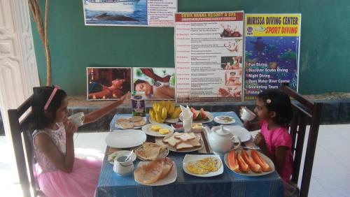 two little girls sitting at a table with food at Suwa Arana Resort in Mirissa