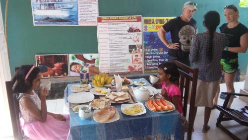 a group of people standing around a table with food at Suwa Arana Resort in Mirissa