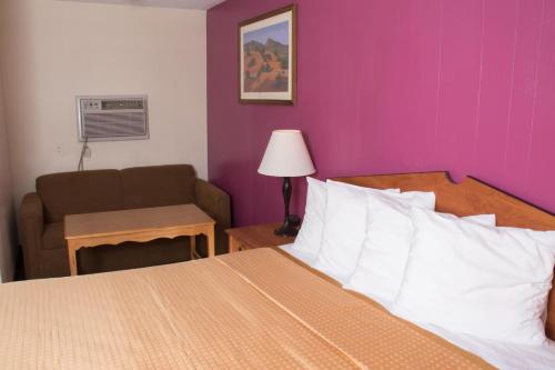 a bedroom with a bed and a chair and a couch at Budget Inn in Caldwell