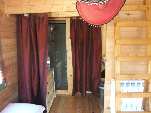 a bedroom with red curtains in a log cabin at Gite La Paillote in Montauroux