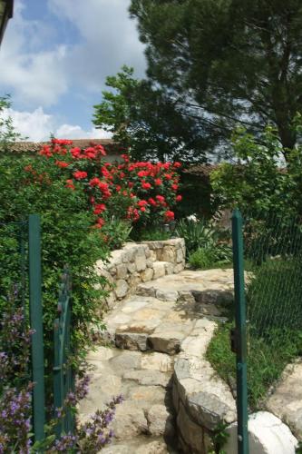 a garden with red flowers and a fence at Gite La Paillote in Montauroux