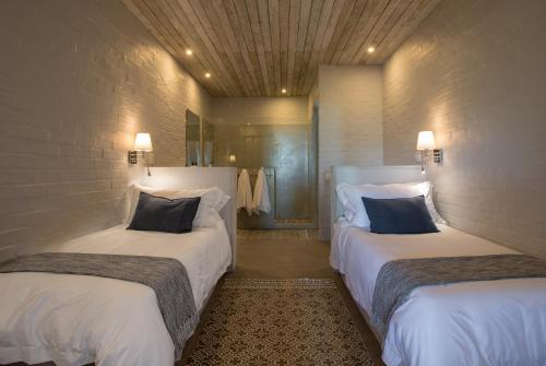 a bedroom with two beds with white sheets and blue pillows at The Quarter Deck in Kenton on Sea
