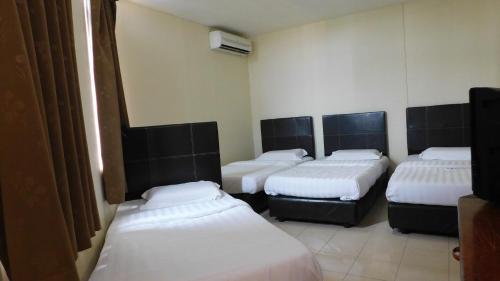 a group of four beds in a room at Hotel Ocean in Lahad Datu