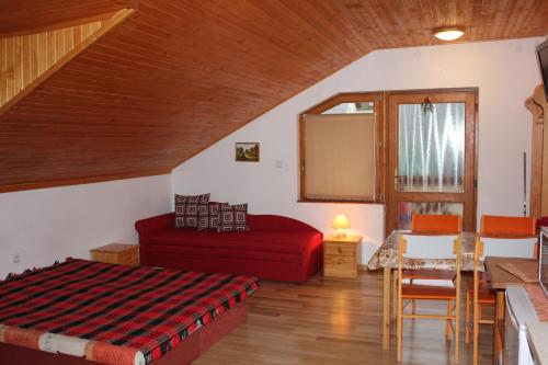 ein Wohnzimmer mit einem roten Bett und einem Tisch in der Unterkunft Apartmany u Janka Vinné Jazero in Vinné