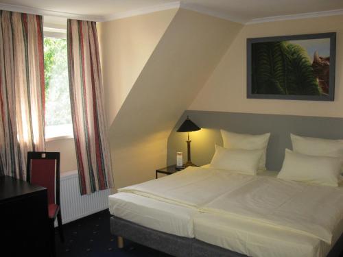 a bedroom with a white bed and a window at Löns Hotel Garni in Garbsen