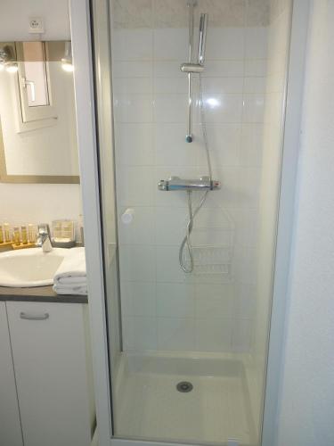 une douche avec une porte vitrée à côté d'un lavabo dans l'établissement Les Jardins Du Golf – Mandelieu, à Mandelieu-la-Napoule