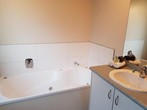 a bathroom with a bath tub and a sink at Portmans Motor Lodge in Hastings