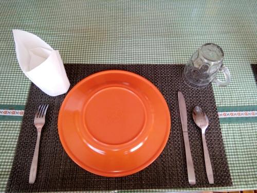 an orange plate and utensils on a table at Novita Homestay in Bunaken