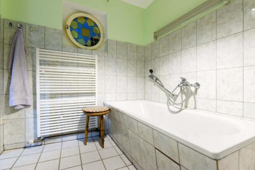 a bathroom with a tub and a stool and a window at Cottage near centrum, paradise in Berlin