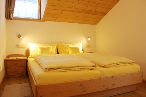 - une chambre dotée d'un grand lit avec des draps jaunes dans l'établissement Haus Waldruhe, à San Candido