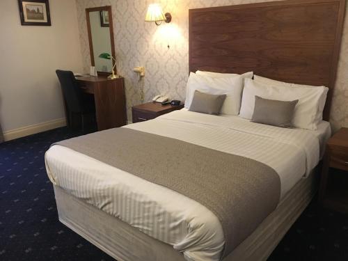 a hotel room with a large bed with white sheets and pillows at Normanton Park Hotel, Sure Hotel Collection by Best Western in Oakham
