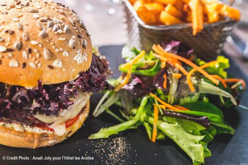 a sandwich and a salad on a black plate at Hotel Les Arolles in Méribel