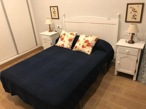sypialnia z łóżkiem z niebieską pościelą i 2 szafkami nocnymi w obiekcie Infantes 8-4-30 w mieście Sanlúcar de Barrameda