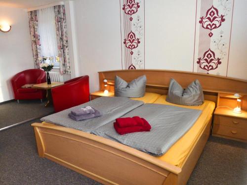 a bedroom with a bed with two red pillows on it at Pension Haus Rodenstein in Altenbrak