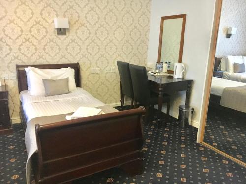 a hotel room with a bed and a desk and a mirror at Normanton Park Hotel, Sure Hotel Collection by Best Western in Oakham